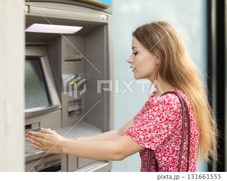 Woman uses ATM, withdraws cash from card. Girl buys travel ticket from machine Woman uses ATM, withdraws cash from card. Girl buys travel ticket from machine 131661555