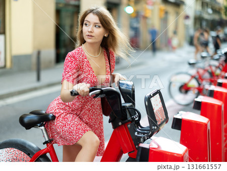 young woman stands near a bicycle rental point 131661557