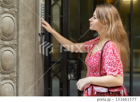 Young woman standing near intercom Young woman standing near intercom 131661577
