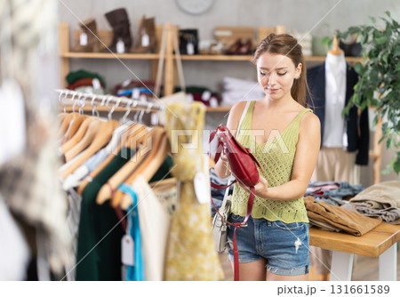 Young girl shopping - choosing a fashionable handbag in clothing store Young girl shopping - choosing a fashionable handbag in clothing store 131661589