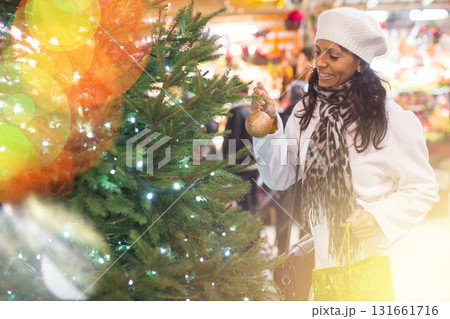 Positive hispanic woman choosing green Christmas tree at city fair 131661716
