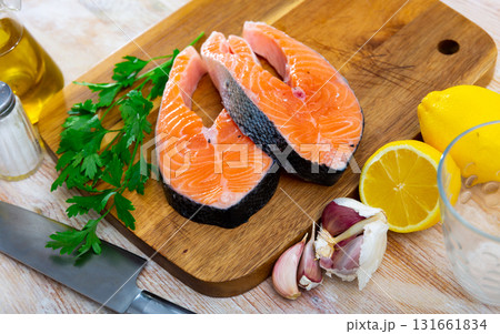 Salmon fillet on cutting board with lemon and parsley Salmon fillet on cutting board with lemon and parsley 131661834