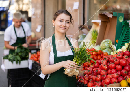 Women seller offers green onions at the market Women seller offers green onions at the market 131662072