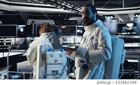 Astronaut checking human expansion in space mission data on laptop during cosmic journey. Orbit station crew managing systems using notebook during mankind survival expedition 131662109