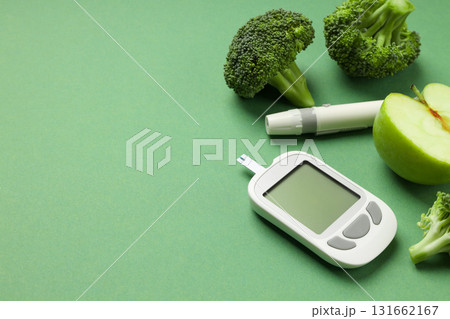 Diabetes testing equipment next to fresh broccoli and green apple Diabetes testing equipment next to fresh broccoli and green apple 131662167