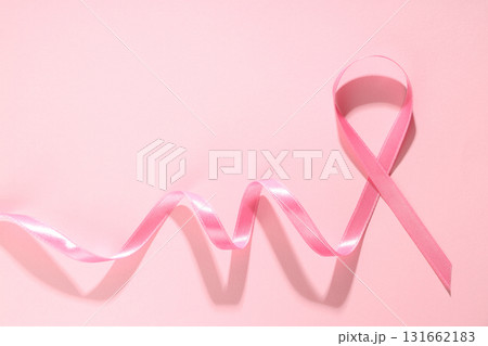 Pink ribbon laid on soft pink surface represents awareness 131662183