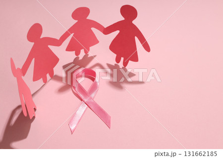 Paper figures holding hands with a pink ribbon on pink background 131662185