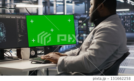 Data center programmer coding on green screen PC, monitoring AI systems. Server hub IT expert uses mockup computer to oversee rackmounts powering deep learning processes, camera A 131662258