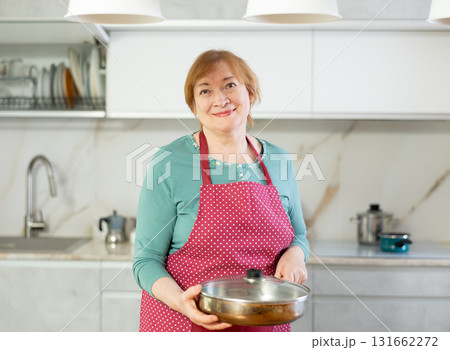 Portrait of a positive woman in an apron with a frying pan Portrait of a positive woman in an apron with a frying pan 131662272