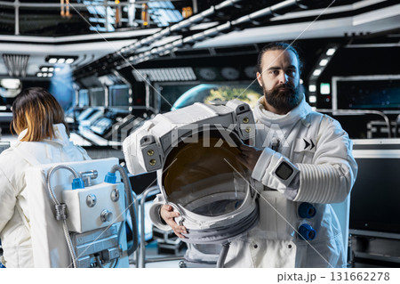 Portrait of astronaut holding helmet preparing for scientific mission, operating spacecraft. Spaceship crew member in spacesuit wearing equipment preparing for planetary exploration mission Portrait of astronaut holding helmet preparing for scientific mission, operating spacecraft. Spaceship crew member in spacesuit wearing equipment preparing for planetary exploration mission 131662278