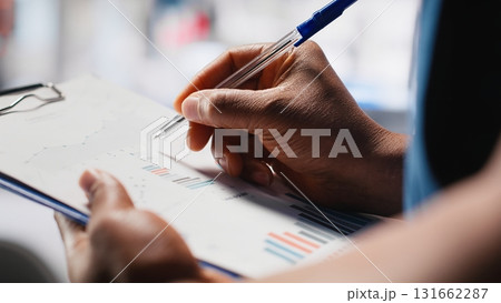 Black photovoltaics factory specialist checking configuration files, analyzing data to ensure seamless production. Solar panels manufacturing plant employee reading user manual. Camera A. 131662287