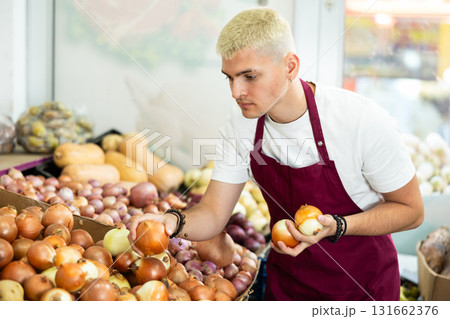 Guy shop seller puts onion goods on display case Guy shop seller puts onion goods on display case 131662376
