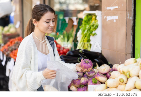 Girl shopper choosing ripe radish at street market Girl shopper choosing ripe radish at street market 131662378