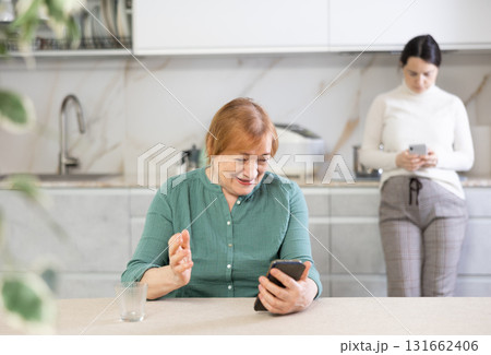 Portrait of a happy mature woman reading messages on her mobile 131662406