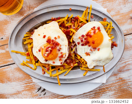 Fried eggs with french fries sprinkled with cured ham 131662452