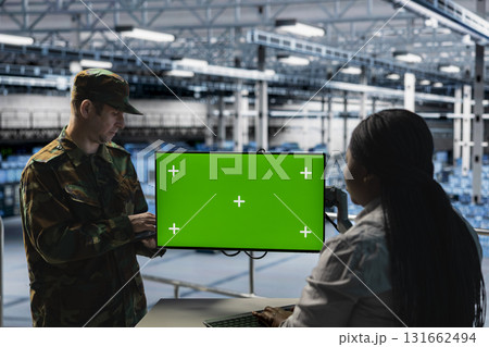 Teamworking soldiers in server hub doing brainstorming, checking reports on green screen display. Team of army information experts working together, monitoring systems using chroma key monitor 131662494