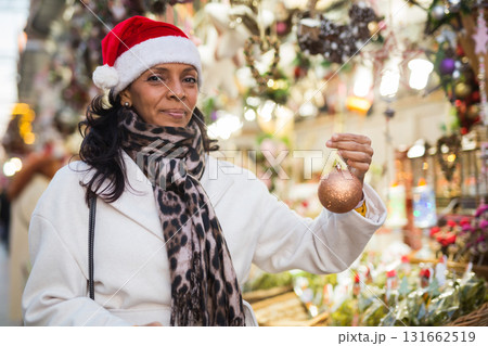 Latin American woman chooses Christmas souvenirs and toys Latin American woman chooses Christmas souvenirs and toys 131662519