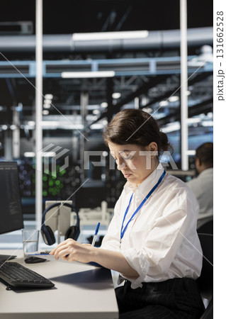 Server room worker holding clipboard, following procedures to evaluate system performance metrics. Woman in data center going over maintenance fixes list, running diagnostics on equipment. Server room worker holding clipboard, following procedures to evaluate system performance metrics. Woman in data center going over maintenance fixes list, running diagnostics on equipment. 131662528