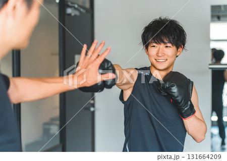 ジム,トレーニングジムでボクササイズをする若いアジア人男性とトレーナーの男性スタッフ 131664209