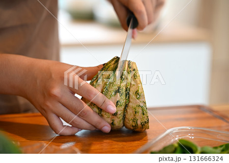 Close up of hands slicing a fresh pumpkin on a wooden cutting board in the kitchen, concept of clean eating Close up of hands slicing a fresh pumpkin on a wooden cutting board in the kitchen, concept of clean eating 131666324