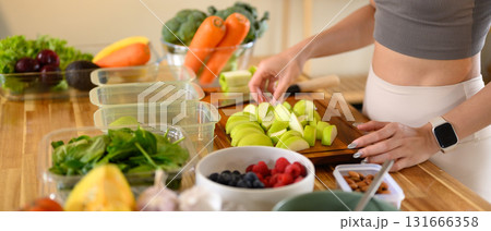 Fitness woman packing nutritious ingredients or weekly meal prep in a bright kitchen Fitness woman packing nutritious ingredients or weekly meal prep in a bright kitchen 131666358