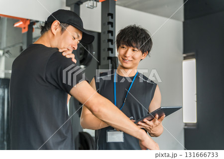 パーソナルジムで会員に個別指導するトレーナーの男性 131666733