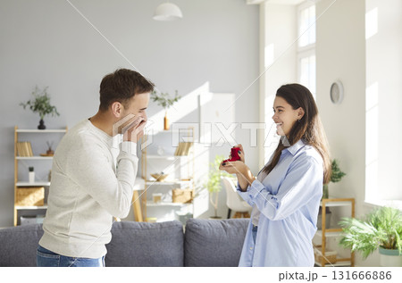 Woman proposing to boyfriend giving present gift box with an engagement ring. 131666886