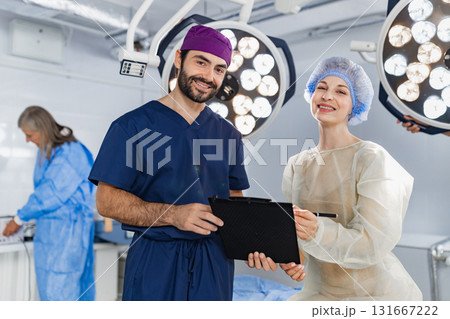 A surgeon and a patient smiling in an operating room, with another medical professional in the background. A surgeon and a patient smiling in an operating room, with another medical professional in the background. 131667222