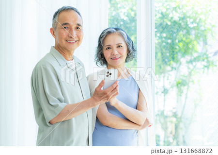 リビングでスマホを見るシニア夫婦 リビングでスマホを見るシニア夫婦 131668872