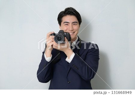 白背景でカメラを構えるスーツの男性 白背景でカメラを構えるスーツの男性 131668949