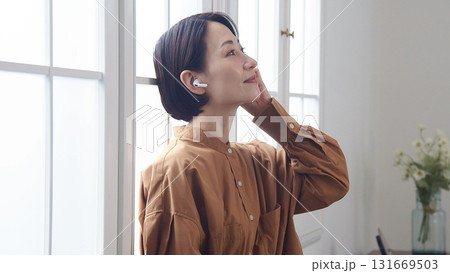 窓際で音楽やラジオを聴いている女性 131669503
