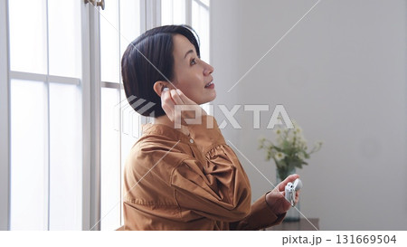窓際で音楽やラジオを聴いている女性 131669504