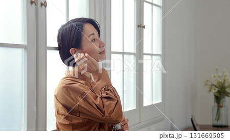 窓際で音楽やラジオを聴いている女性 131669505