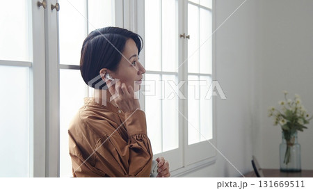 窓際で音楽やラジオを聴いている女性 131669511