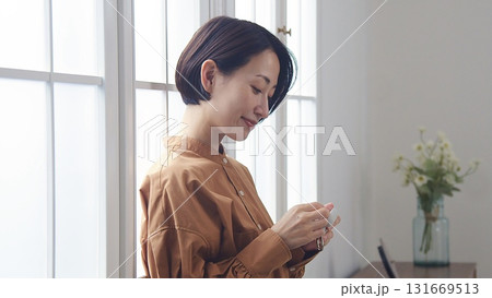 窓際で音楽やラジオを聴いている女性 131669513