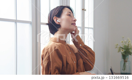 窓際で音楽やラジオを聴いている女性 窓際で音楽やラジオを聴いている女性 131669516