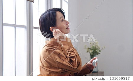 窓際で音楽やラジオを聴いている女性 窓際で音楽やラジオを聴いている女性 131669517