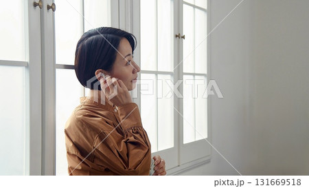 窓際で音楽やラジオを聴いている女性 131669518