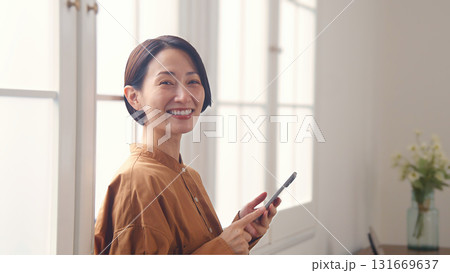 窓際で電話を操作する女性 131669637