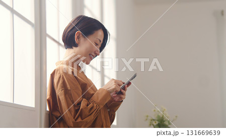 窓際で電話を操作する女性 131669639