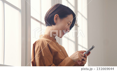 窓際で電話を操作する女性 窓際で電話を操作する女性 131669644