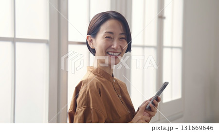窓際で電話を操作する女性 131669646