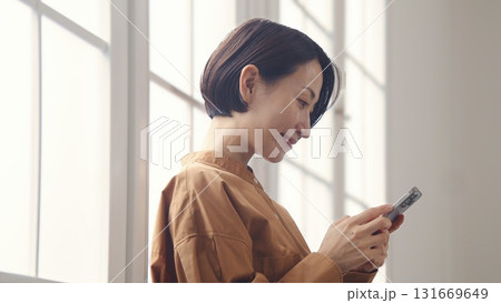 窓際で電話を操作する女性 窓際で電話を操作する女性 131669649