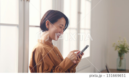 窓際で電話を操作する女性 窓際で電話を操作する女性 131669651