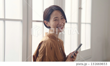 窓際で電話を操作する女性 131669653