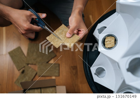 Close-up top view of gardener hands cutting rockwool with scissors, preparing hydroponic media for seed starting, highlighting precision in indoor cultivation techniques. Concept of home gardening. Close-up top view of gardener hands cutting rockwool with scissors, preparing hydroponic media for seed starting, highlighting precision in indoor cultivation techniques. Concept of home gardening. 131670149