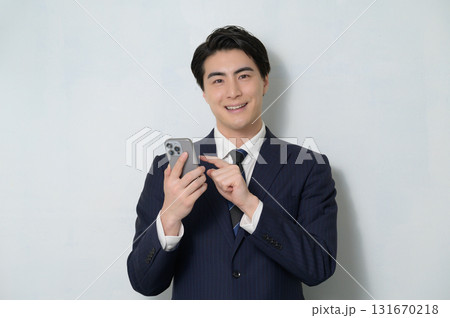白背景でスマホを持つスーツの男性 白背景でスマホを持つスーツの男性 131670218