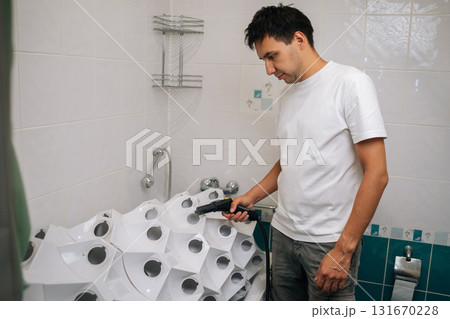 Focused young man sanitizing vertical hydroponic tower garden with steam cleaner in bathroom, highlighting innovative indoor gardening and cleaning technique. Concept of home gardening. 131670228