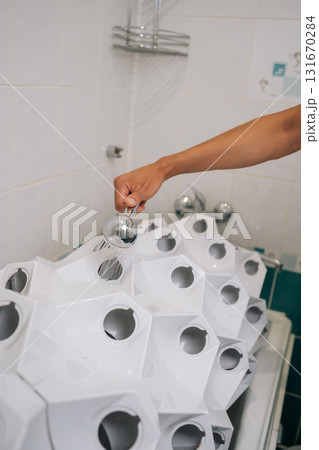 Close-up of male hand holding shower head, watering a hydroponic system in bathroom, showcasing sustainable and innovative approach to indoor gardening. Concept of home gardening. 131670284