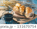 Freshly baked croissants in a plastic container with a hot black coffee cup on a wooden table. Perfect for breakfast or bakery marketing. 131670754